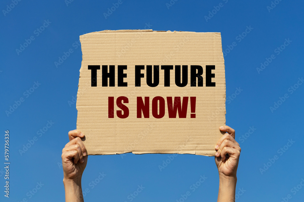 The future is now text on box paper held by 2 hands with isolated blue The future is now text on box paper held by 2 hands with isolated blue