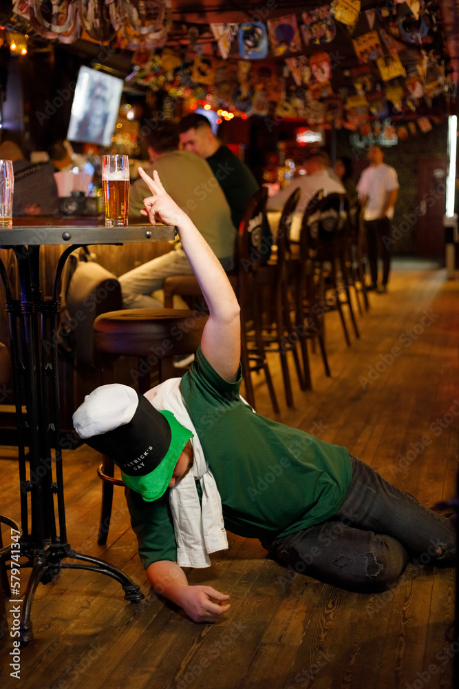 drunk ginger guy in a leprechaun hat for st. patrick's day fell asleep near the bar in the pub