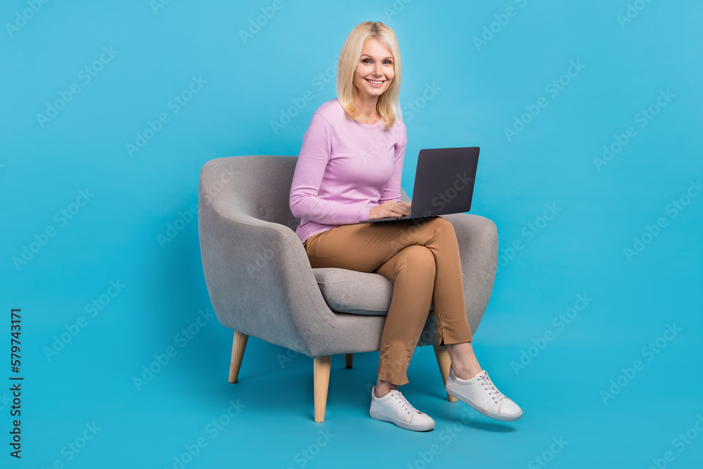 Photo of positive successful lady manager wear stylish clothes sitting chair use netbook device gadget isolated on blue color background Photo of positive successful lady manager wear stylish clothes sitting chair use netbook device gadget isolated on blue color background
