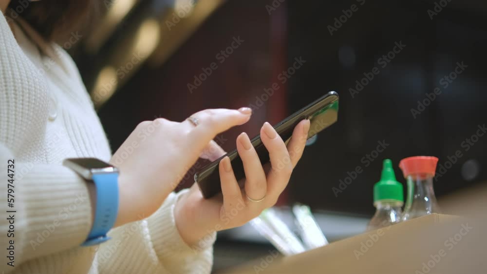 Close view of the female hands using smartphone, texting. Young lady standing at shopping mall. Woman after shopping using smartphone for online shopping Close view of the female hands using smartphone, texting. Young lady standing at shopping mall. Woman after shopping using smartphone for online shopping