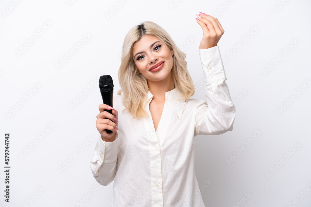 Young singer woman picking up a microphone isolated on white background making money gesture Young singer woman picking up a microphone isolated on white background making money gesture
