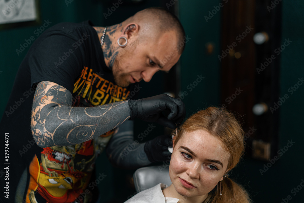 Fototapeta premium Piercing studio - a master pierces a girl's ear