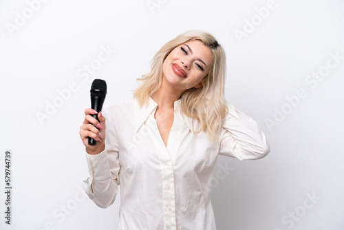 Young singer woman picking up a microphone isolated on white background laughing