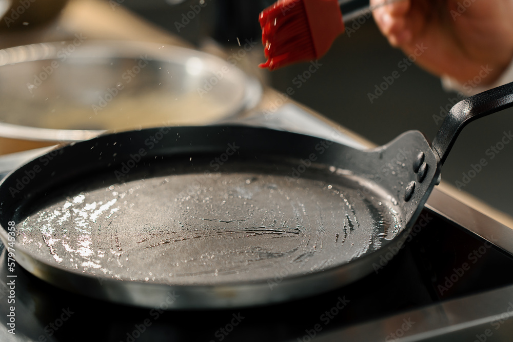 Professional kitchen chef prepares pancakes greasing the pan kitchen utensils