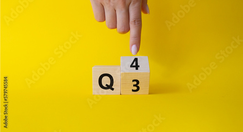 From 3rd Quarter to 4th symbol. Businessman hand points at turned wooden cubes with words 3rd Quarter and 4th Quarter. Beautiful yellow background. Business and Quarter concept. Copy space photo