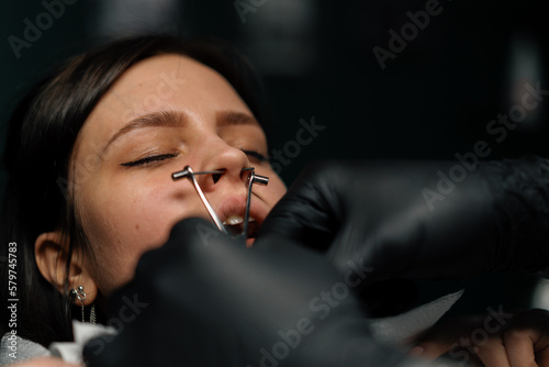 Piercing studio - a master pierces a girl's nose