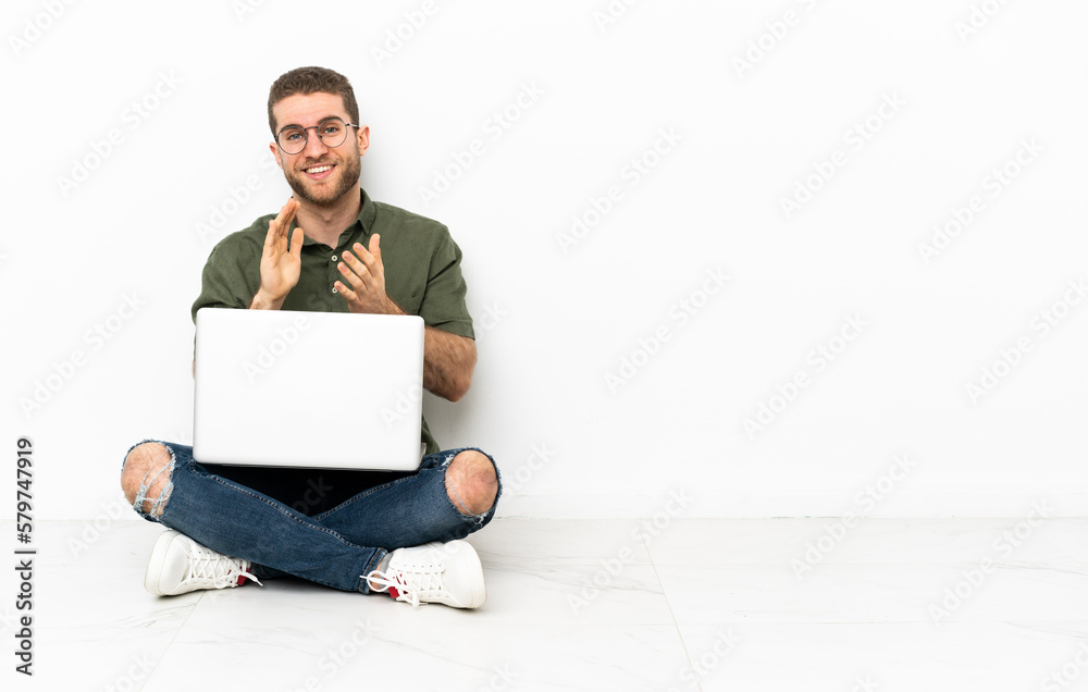 Young man sitting on the floor applauding after presentation in a conference Young man sitting on the floor applauding after presentation in a conference