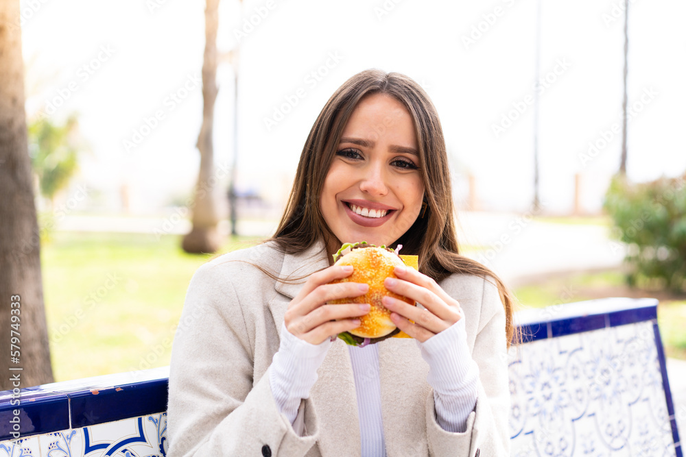 Young pretty woman holding a burger at outdoors