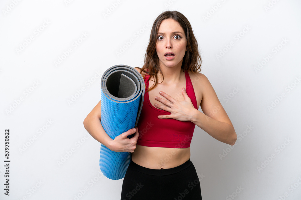 Young sport caucasian woman going to yoga classes while holding a mat isolated on white background surprised and shocked while looking right Young sport caucasian woman going to yoga classes while holding a mat isolated on white background surprised and shocked while looking right
