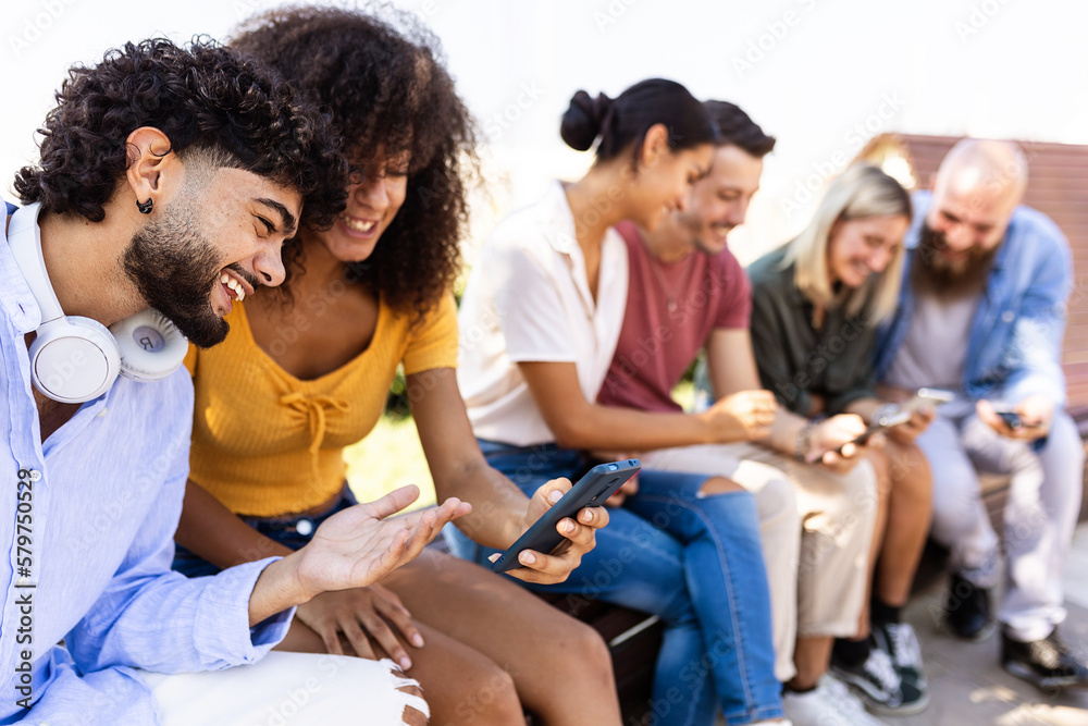 Fototapeta premium Happy young group of student friends having fun together watching social media content on smart mobile phone app