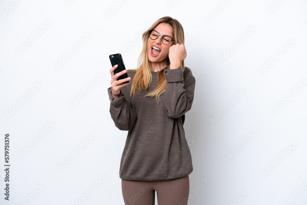 Young Uruguayan woman isolated on white background with phone in victory position Young Uruguayan woman isolated on white background with phone in victory position