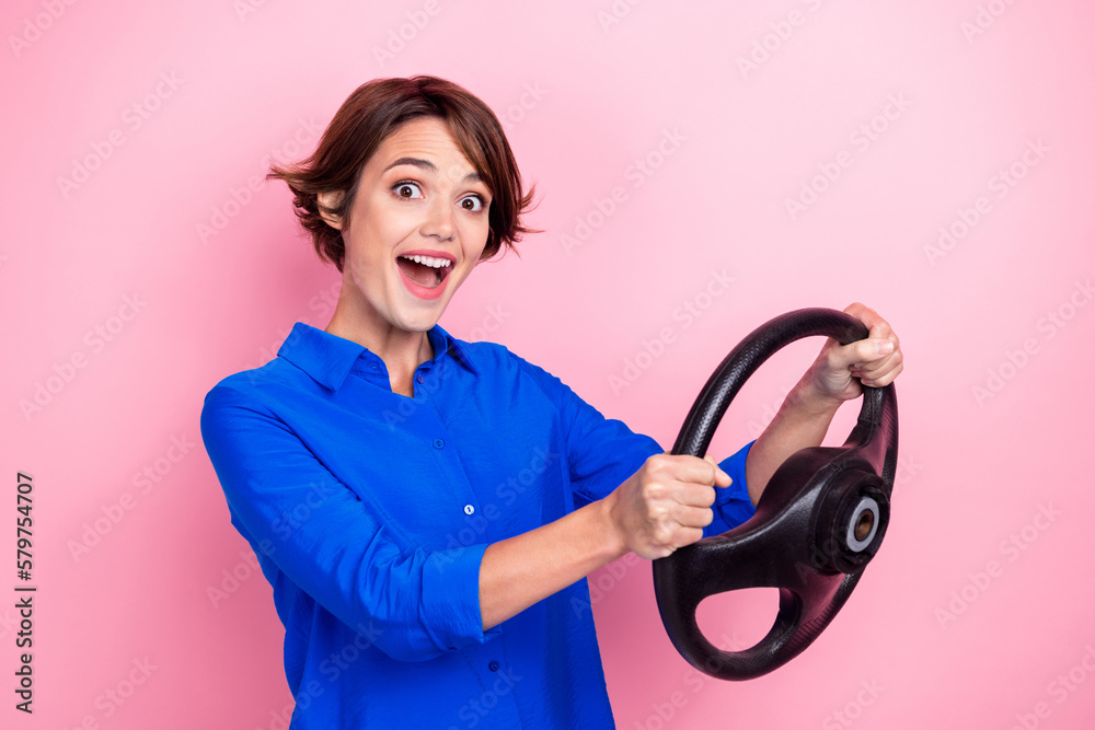 Portrait of astonished cheerful person arms hold wheel toothy smile isolated on pink color background Portrait of astonished cheerful person arms hold wheel toothy smile isolated on pink color background