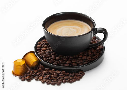 Coffee cup with fresh raw beans and coffee capsules on white background. Creamy breakfast homemade drink