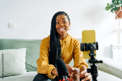 Cheerful black woman recording video on smartphone