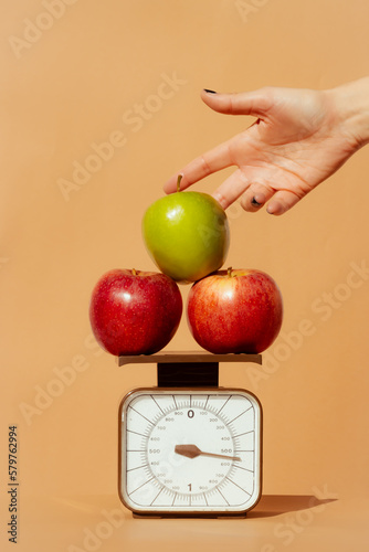 Crop woman weighing fresh apples on scale