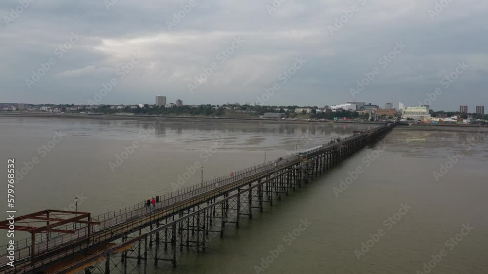 Train driving on tracks on columns above water surface. Long pier and coastal town in background. Southend-on-Sea, UK Train driving on tracks on columns above water surface. Long pier and coastal town in background. Southend-on-Sea, UK