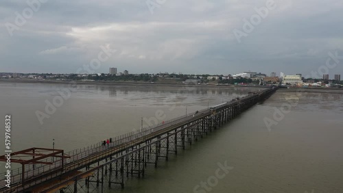 Wallpaper Mural  Train driving on tracks on columns above water surface. Long pier and coastal town in background. Southend-on-Sea, UK Torontodigital.ca