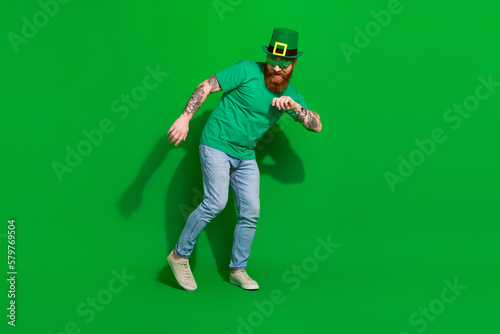 Full length photo of positive funky guy dressed t-shirt shamrock eyewear having fun isolated green color background © deagreez