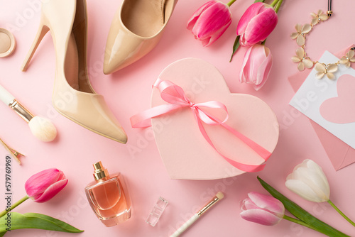 8-march concept. Top view photo of pink heart shaped giftbox tulips beige high heel shoes envelope with letter necklace cosmetic brushes barrette and perfume bottle on isolated pastel pink background