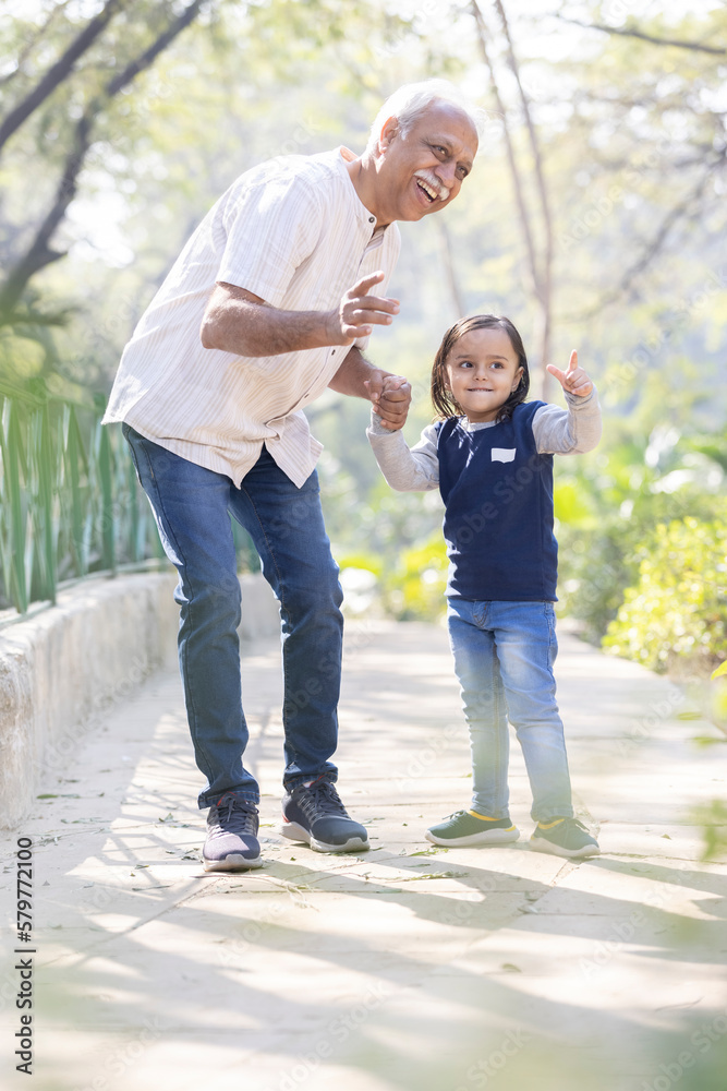 Carefree grandfather having fun with granddaughter at park Carefree grandfather having fun with granddaughter at park