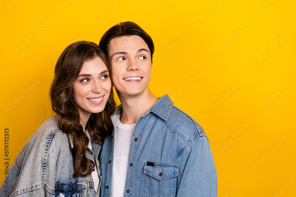 Photo of attractive girl handsome guy touch heads look empty space advert isolated on yellow color background Photo of attractive girl handsome guy touch heads look empty space advert isolated on yellow color background