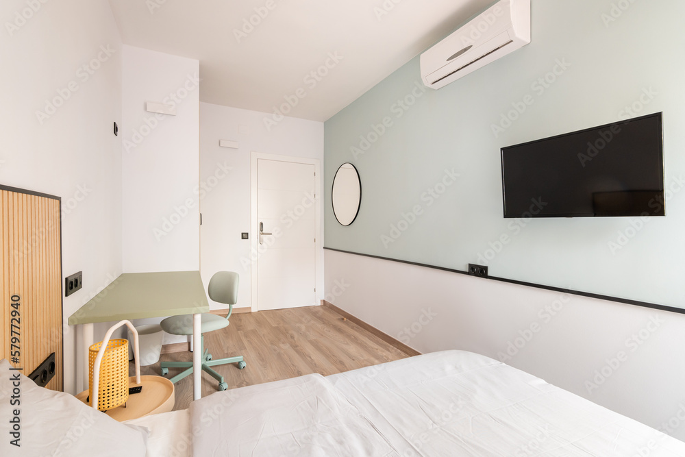 Empty light room with bed, desk, desk and air-conditioner and TV on light green and white wall background. Concept of luxury hotel room or room for a young couple Empty light room with bed, desk, desk and air-conditioner and TV on light green and white wall background. Concept of luxury hotel room or room for a young couple