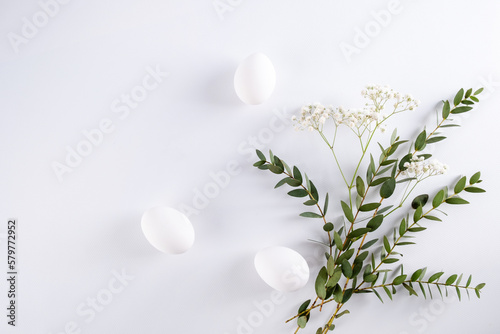 Easter composition made with flowers, eucalyptus branches and eggs on white background  copy space. Creative minimal holiday concept.