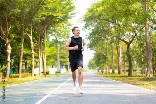 happy young Asian handsome man enjoys his running in city public park during a summer day, sporty guy spend quality time on weekend jogging outdoor in nature for healthy and active lifestyle