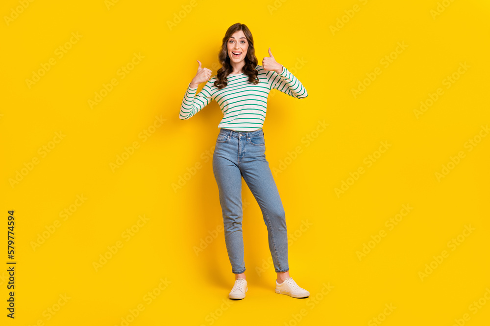 Full size photo of impressed woman curly hairstyle striped shirt astonished staring show likes isolated on yellow color background Full size photo of impressed woman curly hairstyle striped shirt astonished staring show likes isolated on yellow color background