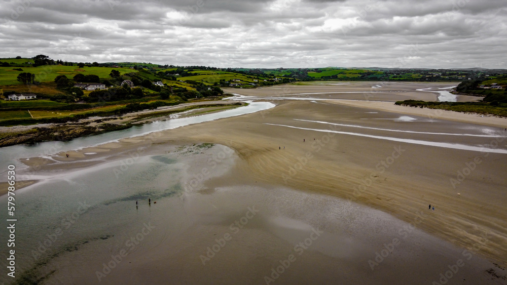 Picturesque Irish beach of Inchydoney, low tide on a cloudy day, top view. The coastline of the island of Ireland. Beautiful green hills on the Atlantic Ocean. Gray clouds in the sky. Picturesque Irish beach of Inchydoney, low tide on a cloudy day, top view. The coastline of the island of Ireland. Beautiful green hills on the Atlantic Ocean. Gray clouds in the sky.