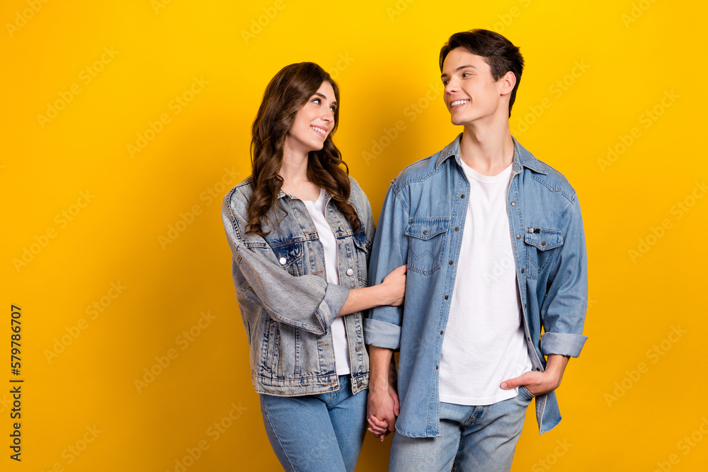 Photo of sweet charming couple dressed denim walking talking empty space isolated yellow color background Photo of sweet charming couple dressed denim walking talking empty space isolated yellow color background