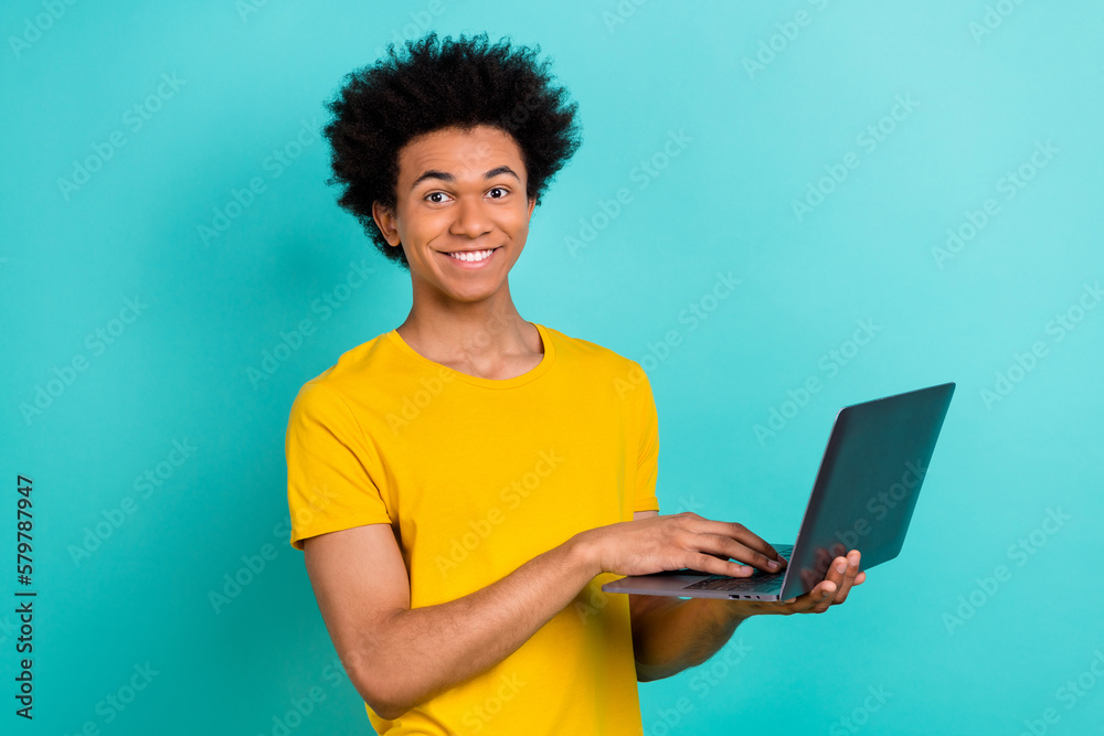 Photo of positive cheerful handsome guy dressed casual t-shirt typing email on laptop remote work isolated on turquoise color background Photo of positive cheerful handsome guy dressed casual t-shirt typing email on laptop remote work isolated on turquoise color background