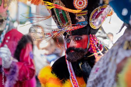 A person in a chinelo costume dancing effusively at a carnival in the State of Mexico