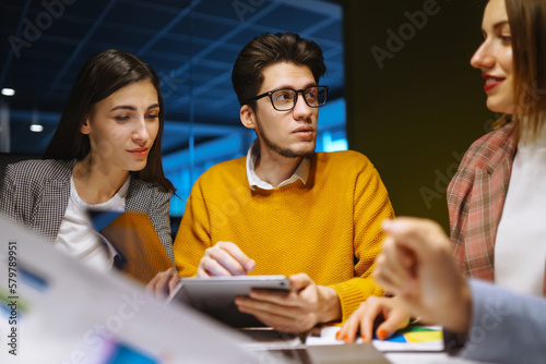Workaholics businesspeople brainstorming financial company ideas analyzing strategy paperwork late at night in business office.Business Partners Discuss Financial Reports, Plan Investment Strategy.