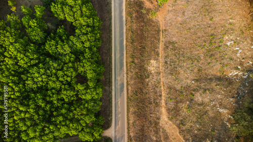 Aerial view of a road that cuts through a lush forest, on the other side is an area destroyed by humans for cultivation of mountain crops. Areas with dense smog and covered with PM2.5. Air pollution
