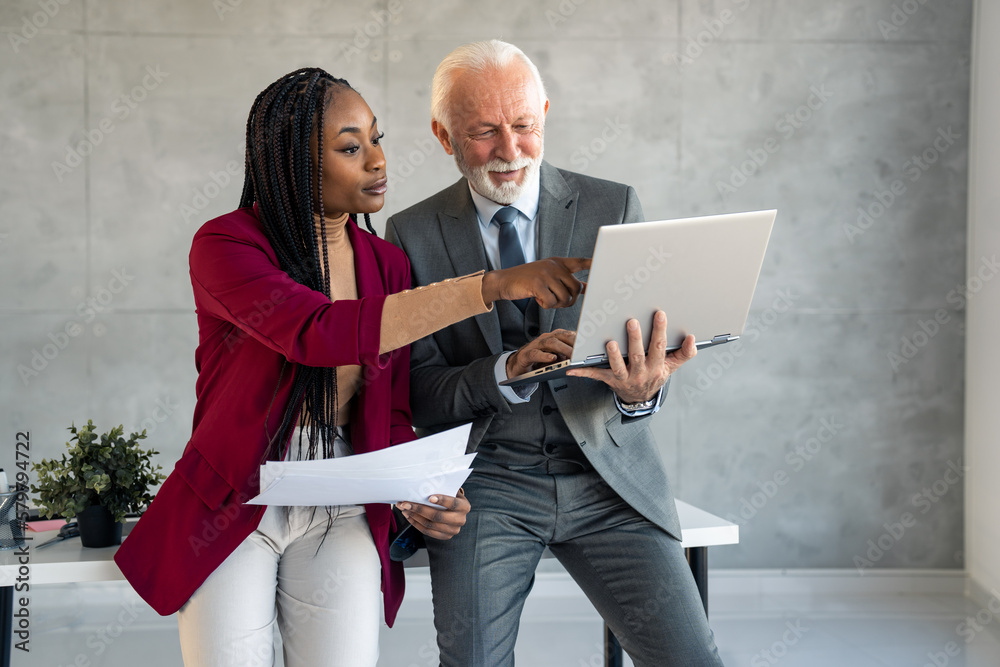 Φωτογραφία Company managers, business professionals handsome senior man and beautiful young woman working together in modern office, discussing strategy ideas, looking at business project presentation on laptop