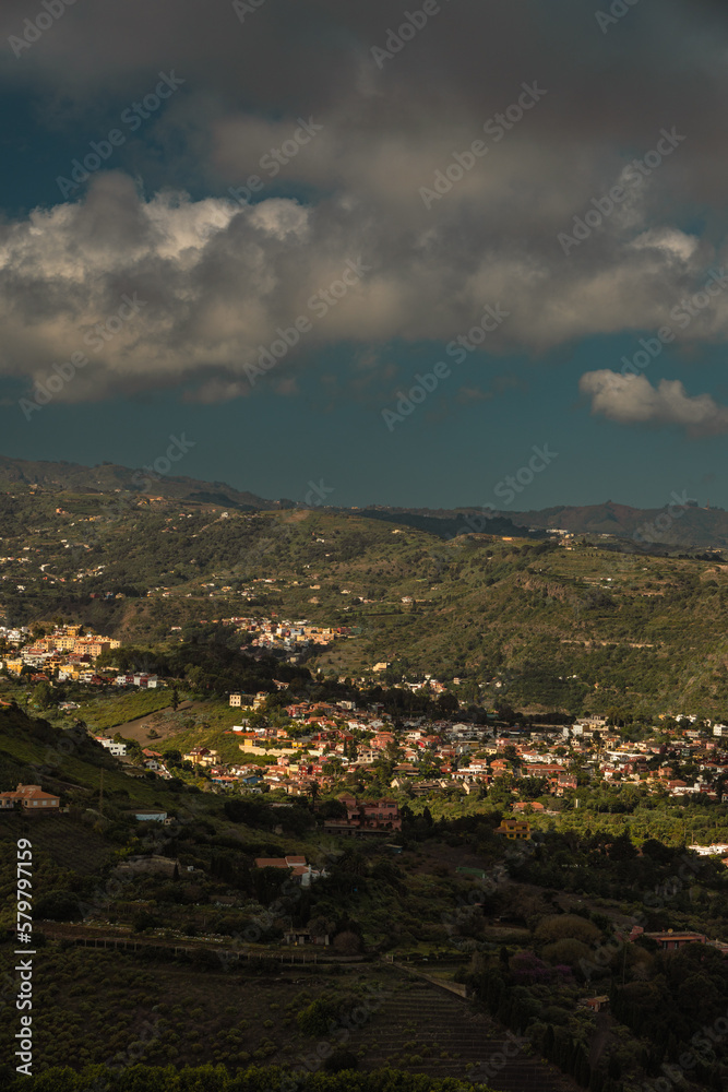 Vertical view of small town on green hillside from viewpoint in Caldera de Bandama crater, Gran Canaria, Spain
