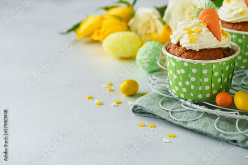 Carrot cake cupcakes for Easter. Carrot cupcakes with cream cheese frosting decorated with tiny marzipan carrots on white background. Happy Easter and spring holiday concept. Holydays homemade dessert