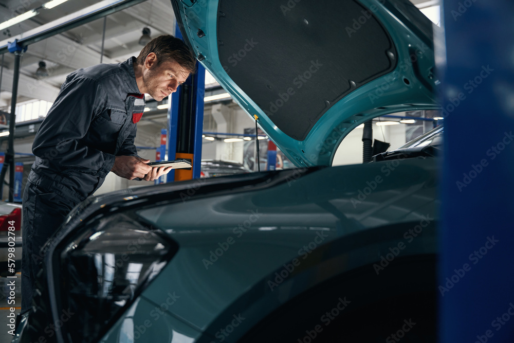 Mechanic in overalls working near the car Mechanic in overalls working near the car
