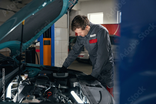 Man in overalls working near the automobile