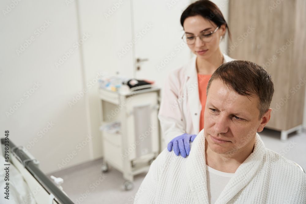 Neat brave patient is receiving support of nurse in hospital Neat brave patient is receiving support of nurse in hospital