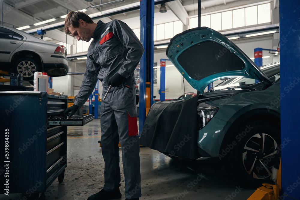 Male chooses tools for car repair in workshop Male chooses tools for car repair in workshop