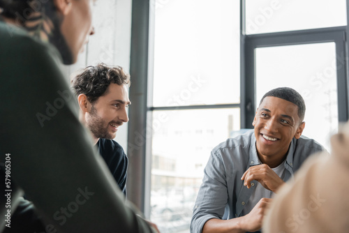 Positive interracial people with alcohol addiction talking during group therapy in rehab center.