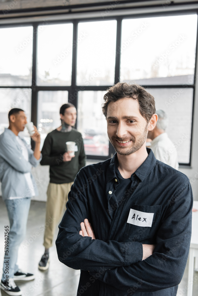 Positive man with name sticker crossing arms during alcoholics meeting in recovery center. Positive man with name sticker crossing arms during alcoholics meeting in recovery center.