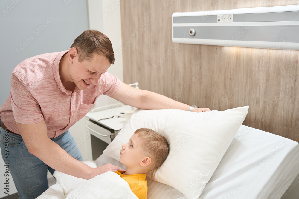 Positive handsome father is talking with little boy in the hospital Positive handsome father is talking with little boy in the hospital