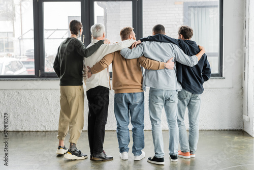 Back view of interracial men hugging during anonymous alcoholics meeting in rehab center. photo