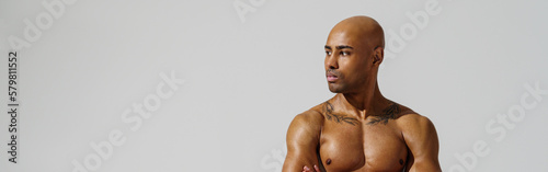 Portrait of attractive sporty man with muscled naked body on white studio background looking at side