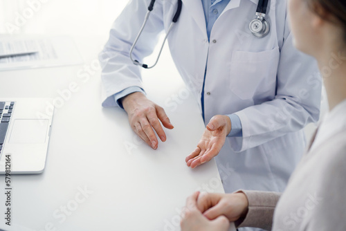Doctor and patient discussing current health questions while sitting at the table in clinic office, only hands closeup. Medicine concept.