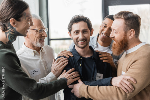 Slika na platnu Multiethnic people hugging smiling man with alcohol addiction during group therapy in rehab center