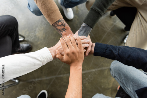 Fotografie Top view of multiethnic people holding hands together during anonymous alcoholics meeting in rehab center